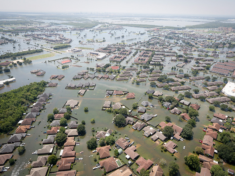 Imagen aérea de un vecindario en Texas inundado. Se observan sólo los techos de las casas y las copas de los árboles.
