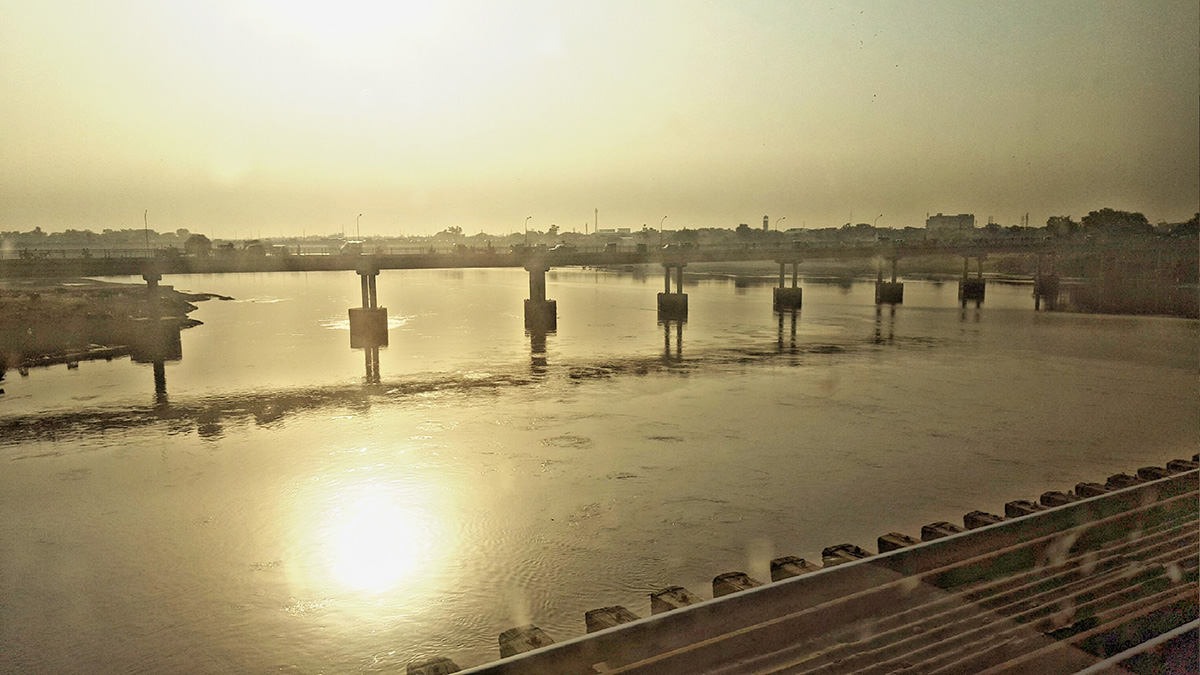 Vehicles cross a bridge over the Ravi River in Lahore, Pakistan, at sunset.