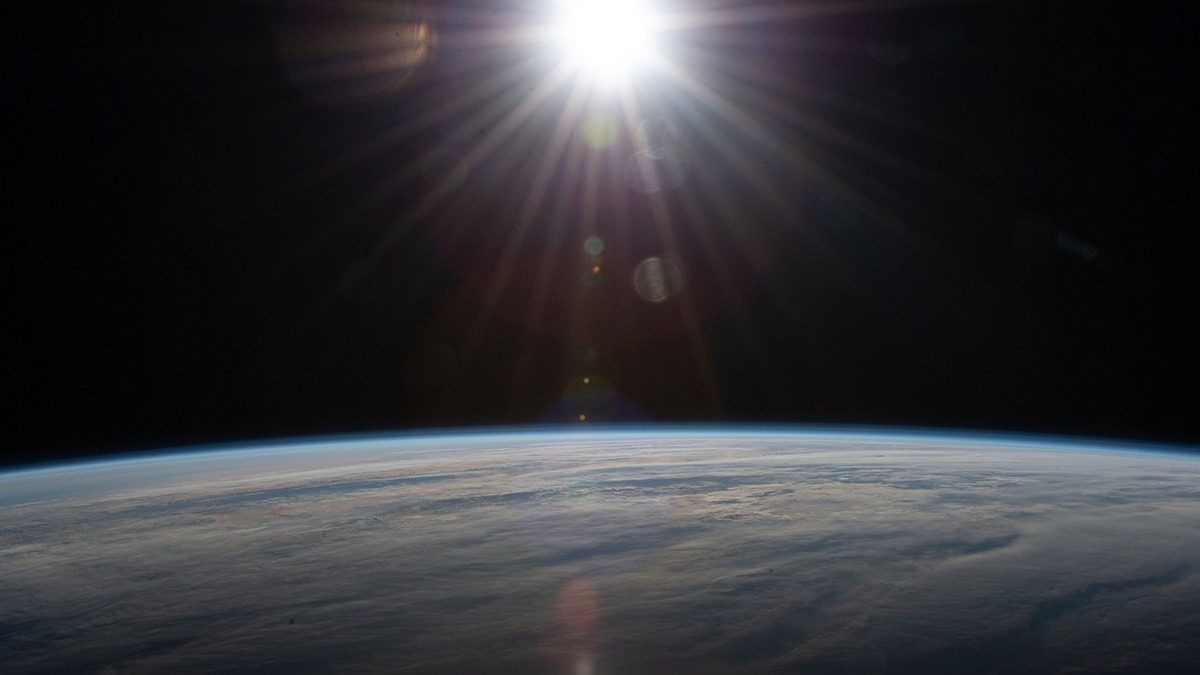 Una explosión de luz solar sobre una Tierra nublada.