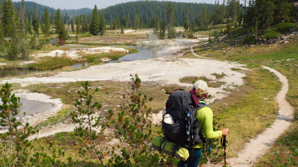 A woman hikes past thermal areas in Yellowstone National Park.
