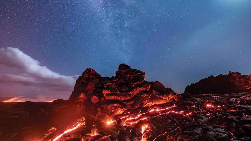 A view of the Milky Way, the moon, Mars, Saturn, and an iridium flare over a surface flow of lava at the Kilauea Volcano in Hawaii