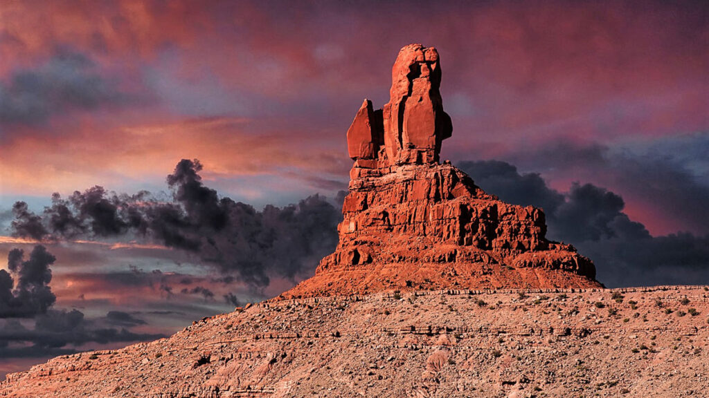 A red rock tower in front of a backdrop of cloudy sky