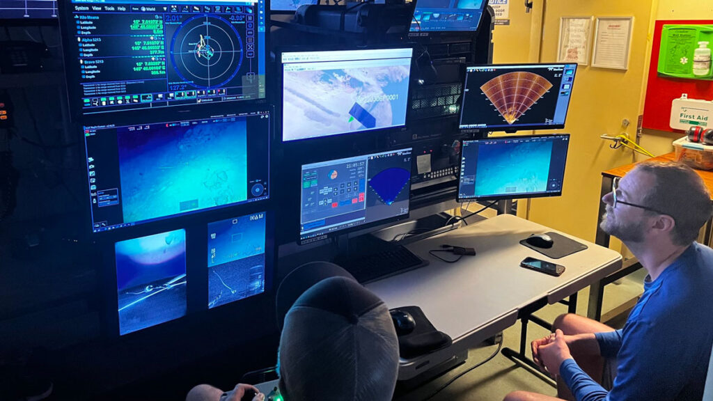 Andrew Pietruszka helps guide the pilot of a remotely operated vehicle exploring underwater sites that may contain aircraft wreckage from WWII.