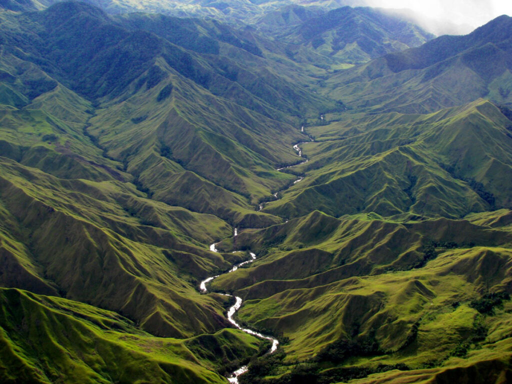 A river threads its way through the green hills of Papua New Guinea.