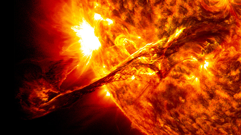 A jet of red plasma shoots out from the Sun’s surface.