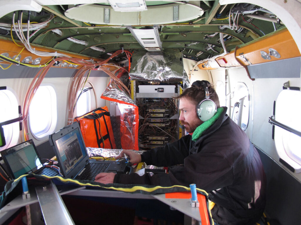 An engineer sits at a computer inside a small airplane
