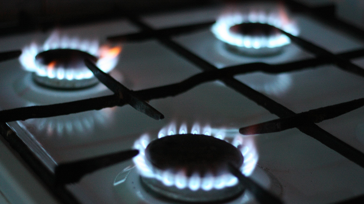 Natural gas burning on kitchen gas stove in the dark. Panel from