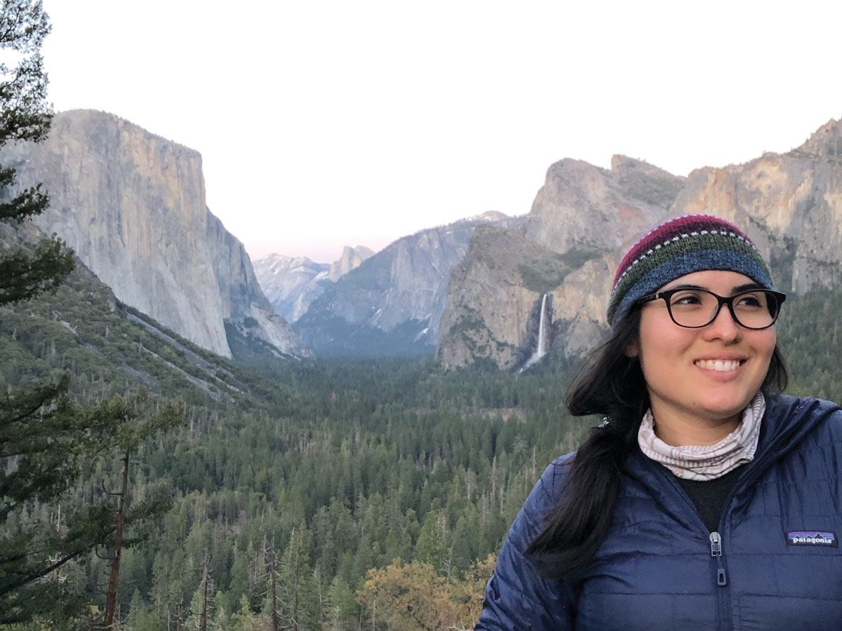Jimena Díaz Leiva standing in front of pine trees and cliff faces in Yosemite National Park.