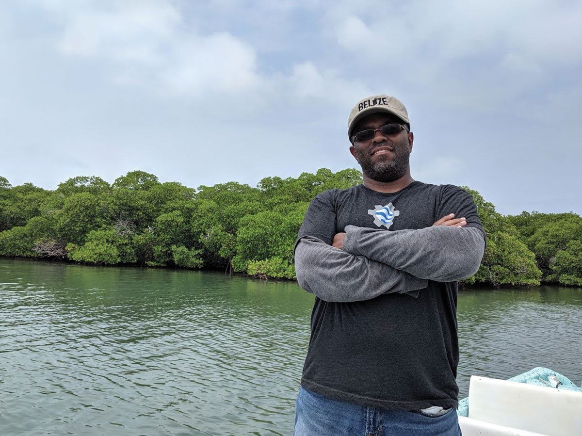 Emil Cherrington stands on a boat in the middle of a river in Belize in May 2019.