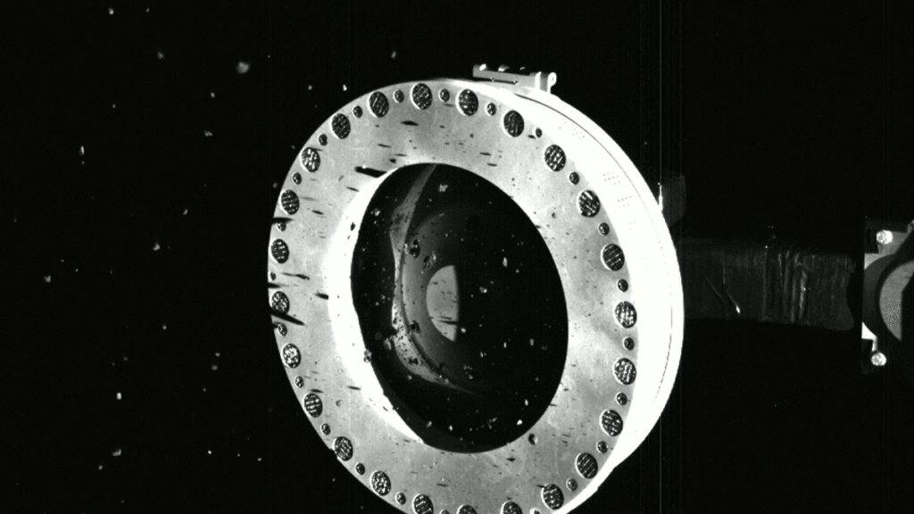 Flaky rock particles leak into space from the over-filled sampling device on OSIRIS-REx in this series of black and white images.