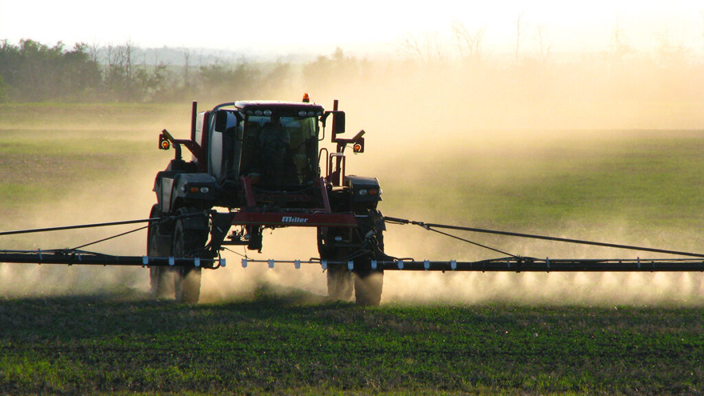 Tractor spraying pesticides on crops in a field