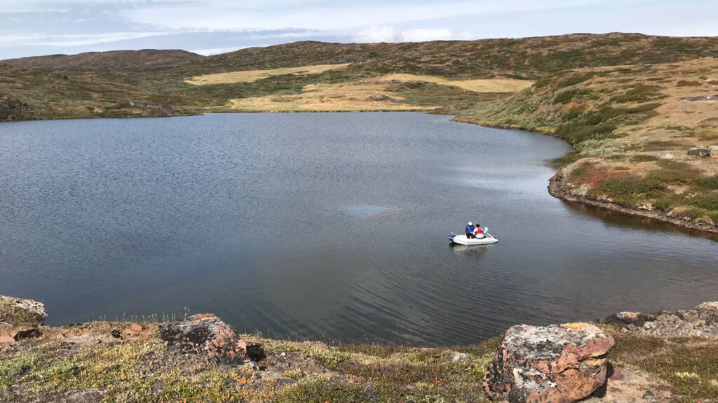 Scientists ride a boat on a lake in Greenland.