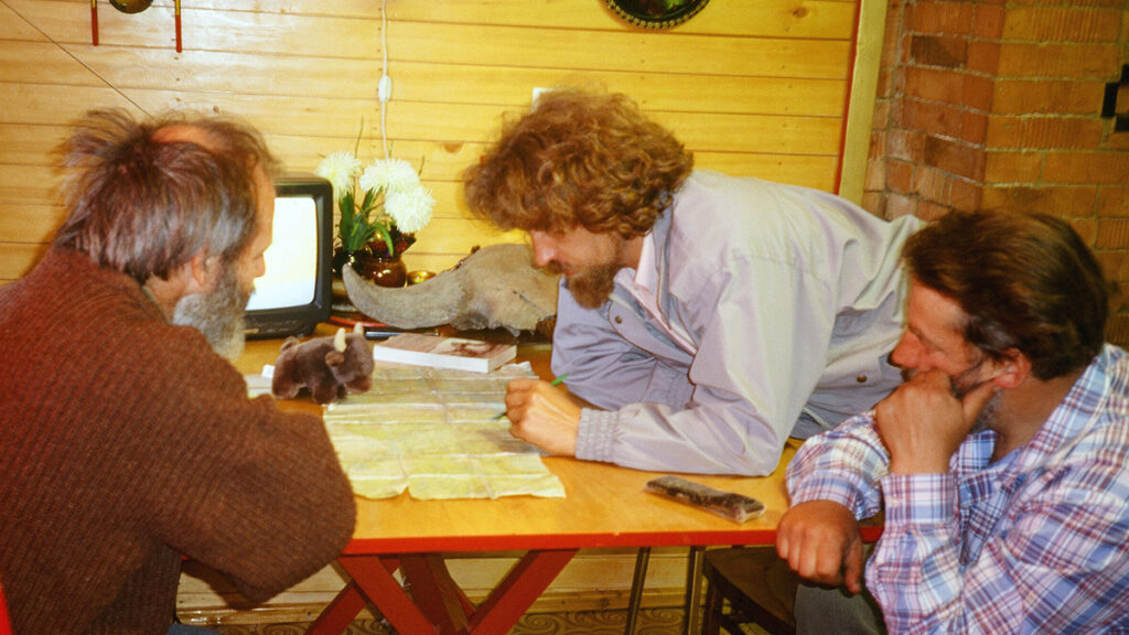 Three scientists discuss around a map on a table.