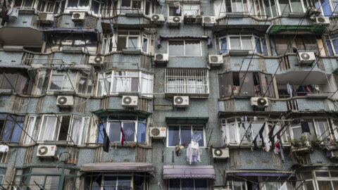 Green building with many windows and white AC fans near each window
