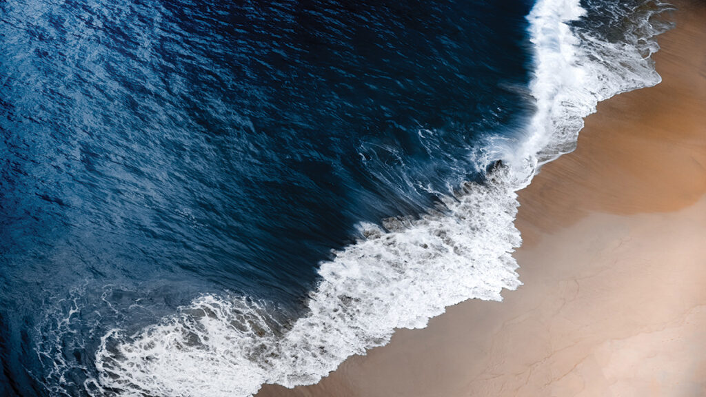 A wave washes ashore on a beach in Bali, Indonesia.