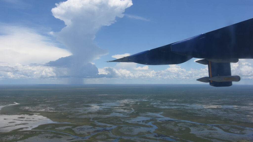 Aerial view of a large wetland area, with part of an airplane wing in the foreground