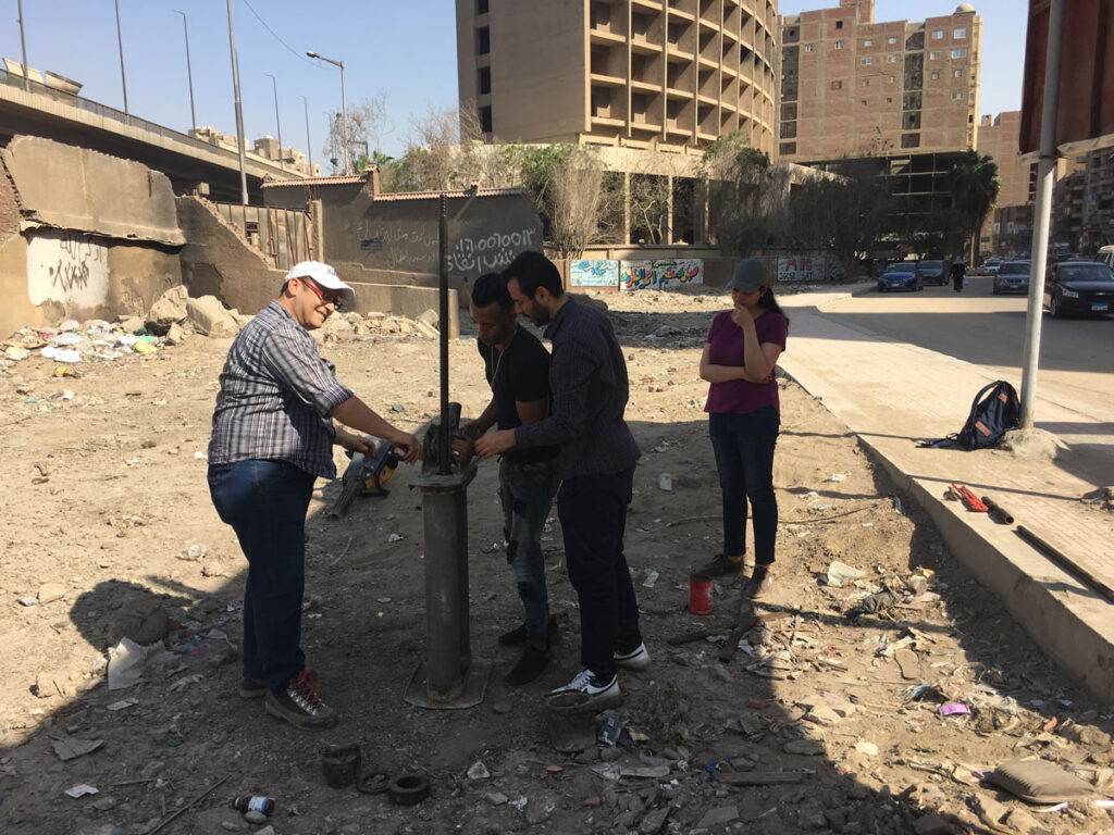 Four people extract a sediment core from an urban lot in Giza, Egypt.