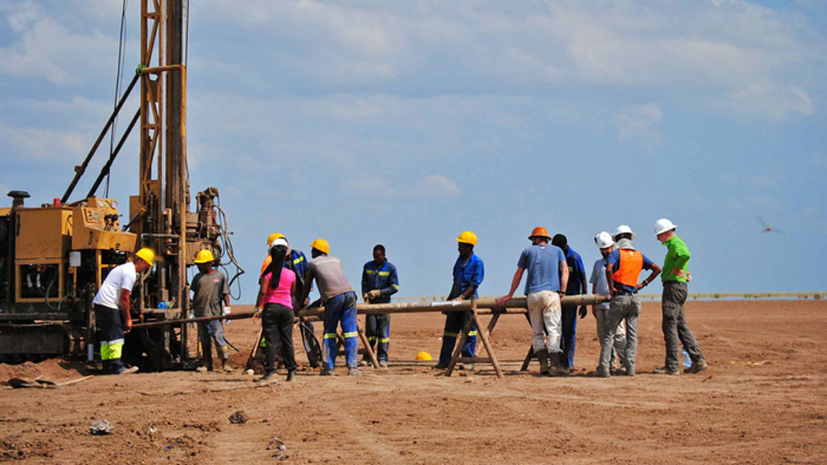 A crew of about a dozen people handle a sediment core at their scientific drilling site at Chew Bahir in Ethiopia.