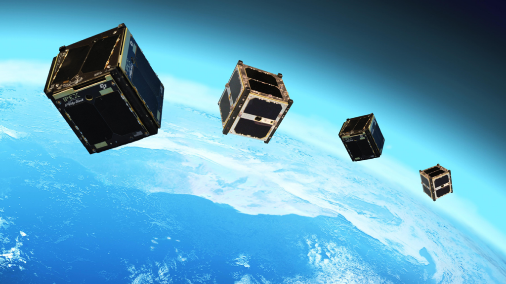 Four CubeSats close together in orbit above Earth.