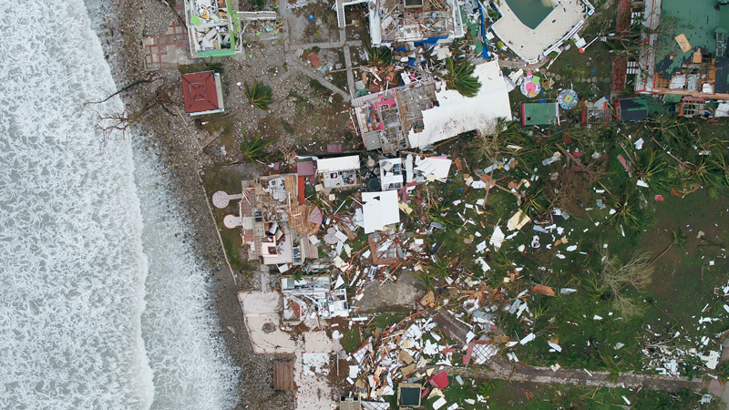 Bird’s-eye view photo of damaged buildings and debris next to a beach