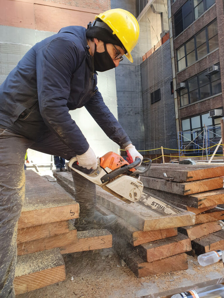 Man saws timber wood planks.