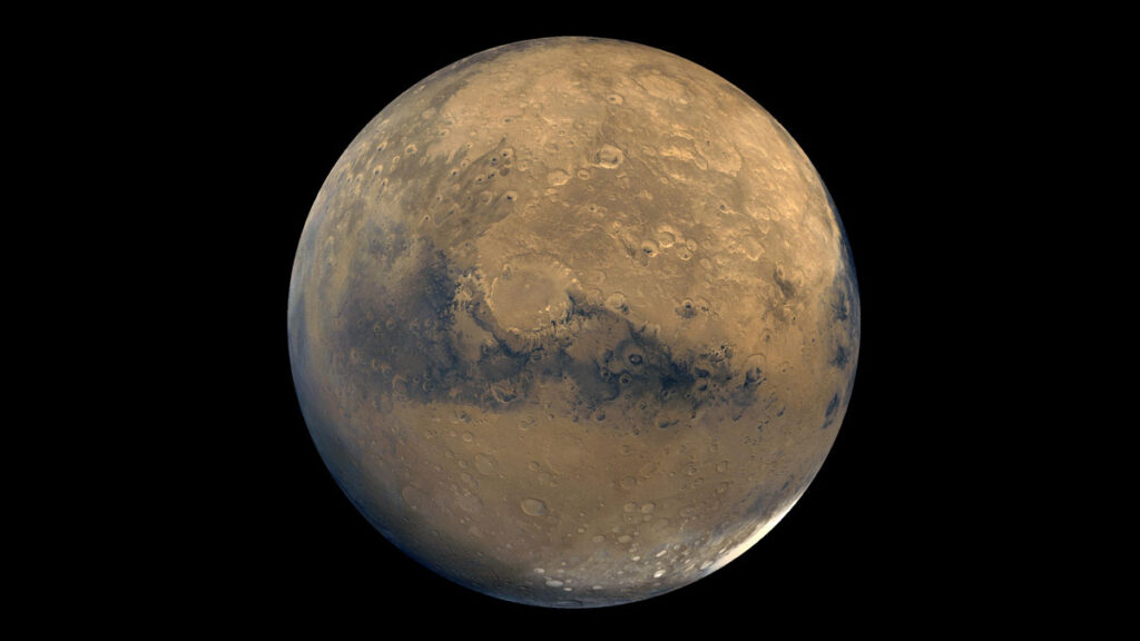 Photo of Mars from space. Red sphere with black patches near center and white areas on two sides.