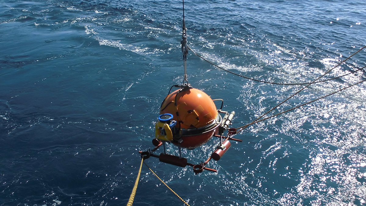 An orb-shaped ocean bottom seismometer descending into the sea surface