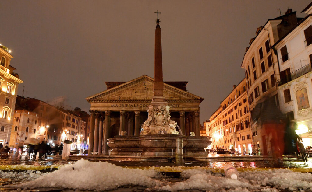 View from ground level of the Pantheon in the Piazza della Rotonda in Rome at night, with small piles of hail in the foreground