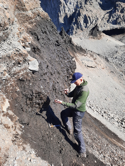 Lead researcher Kristian Svennevig holds and photographs debris from the 2021 landslide.