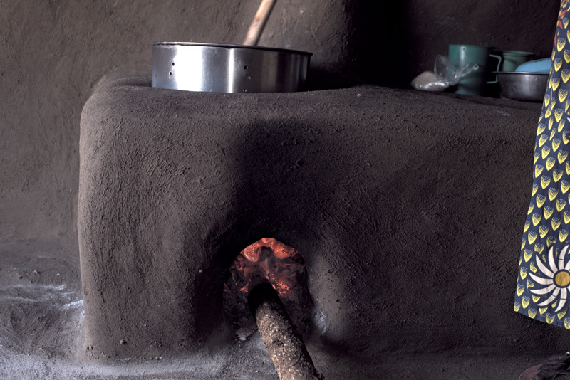 A brown rectangle made of mud with a metal bowl and spoon on top. In the center of the box is a hole with a fire.