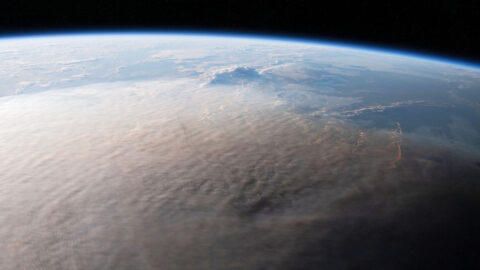 A large gray ash cloud covers the majority of visible Earth in a photo taken from the International Space Station.