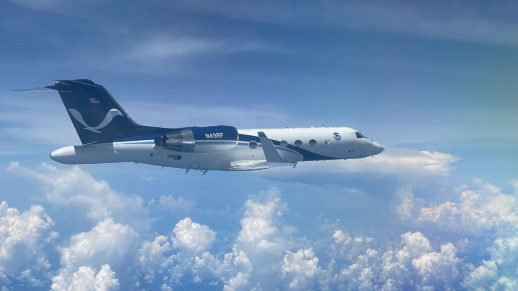 Photo of a jet airplane in flight with clouds in the background.