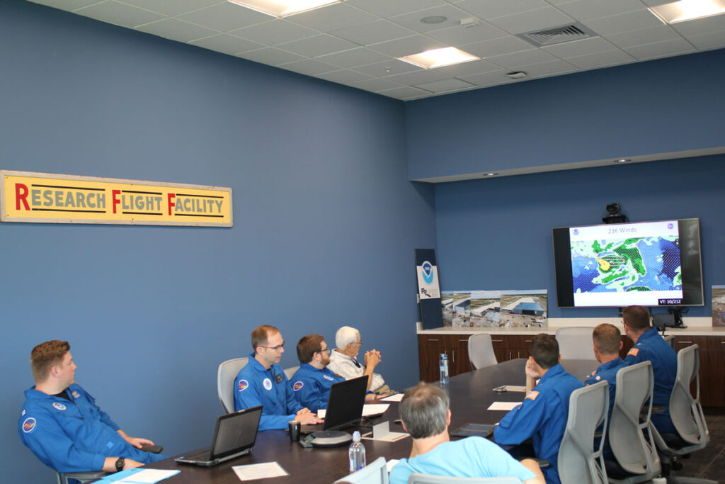 People looking at a large computer screen while sitting in an office.