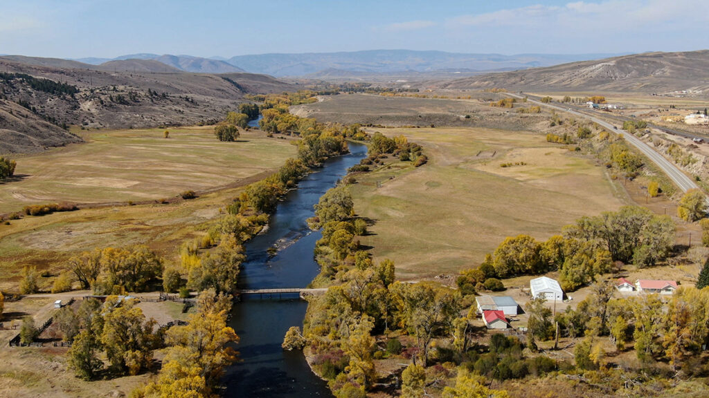 An aerial image of a river flowing through fields of green
