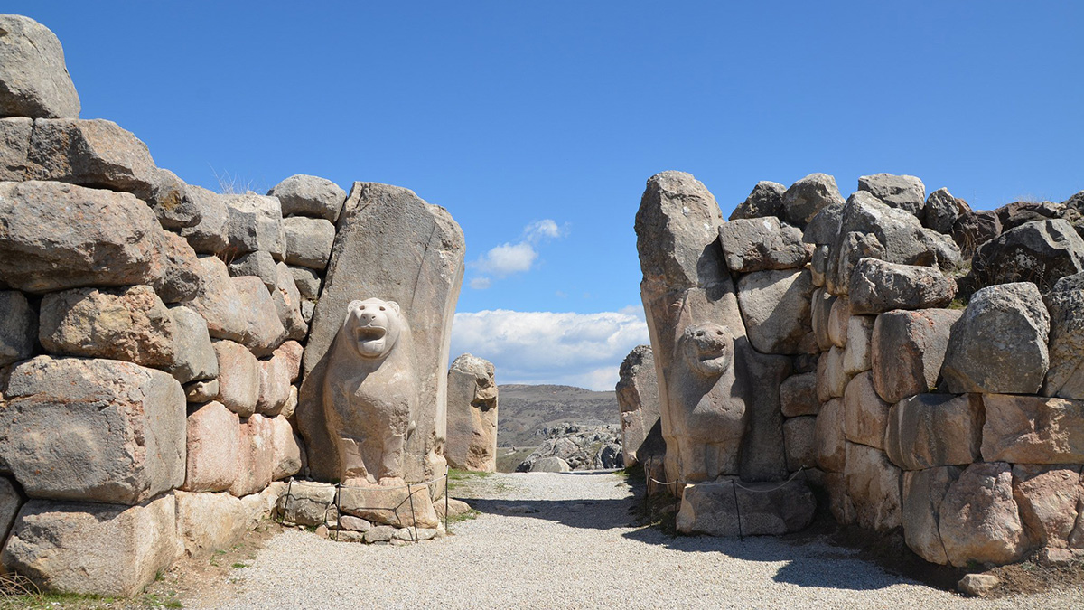 A partially missing stone archway is flanked by stone lionlike statues