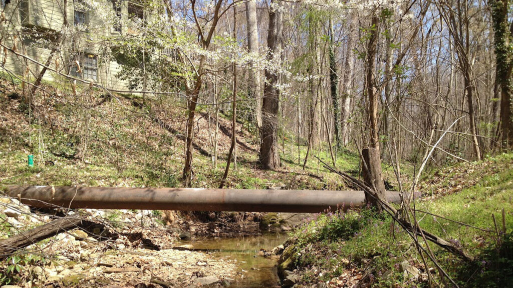 A shallow, narrow creek cuts through the backyard of a home.