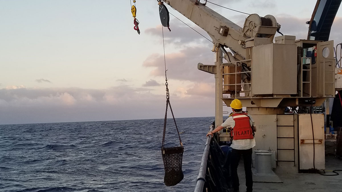 Darin Schwartz, a postdoctoral researcher at Boise State University, directs deployment of a rock dredge in the South Pacific from the deck of the R/V Atlantis in 2019.