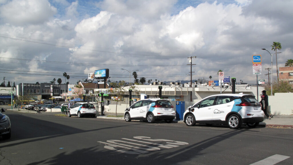 Electric and hybrid cars parked alongside a road charge at plug-in stations