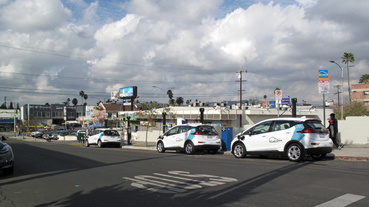 Vehículos híbridos y eléctricos blancos formados para cargar en una estación.