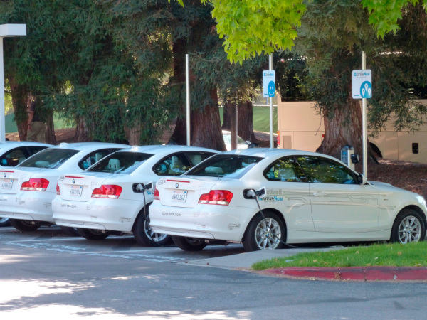 Una fila de autos en un estacionamiento conectado a estaciones de carga.