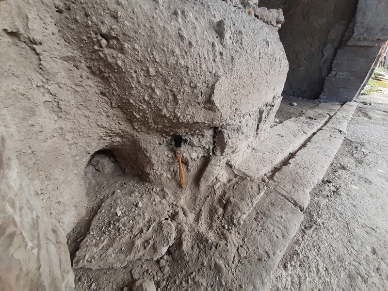 A paintbrush leans against a fragmented wall of ash.