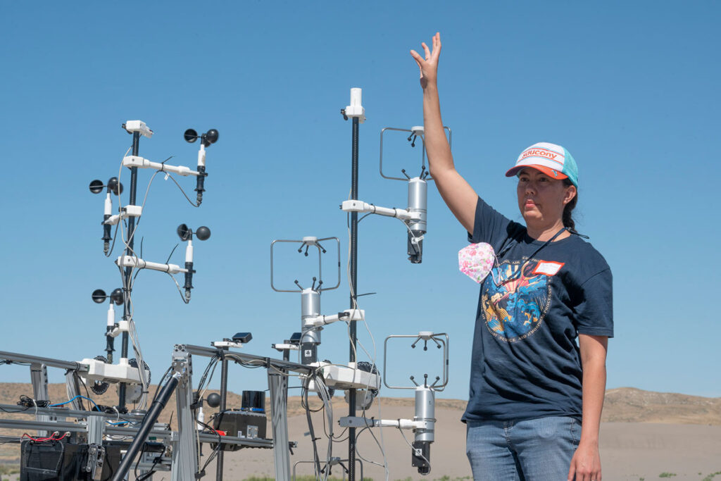 A person raises their right arm beside a metal framework equipped with various sensors.