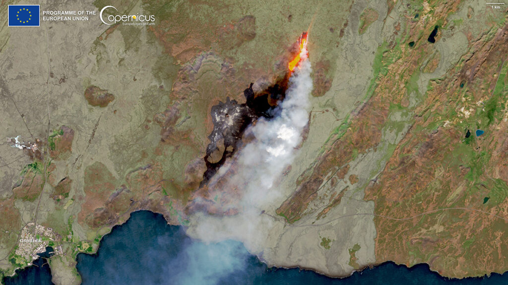 Una imagen de satélite de una masa continental con parches cafés y verdes. Al centro hay una nube de humo con una línea naranja brillante.