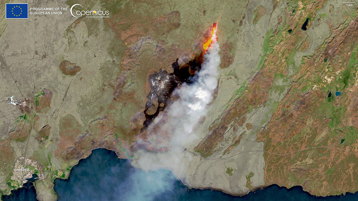 Una imagen de satélite de una masa continental con parches cafés y verdes. Al centro hay una nube de humo con una línea naranja brillante.