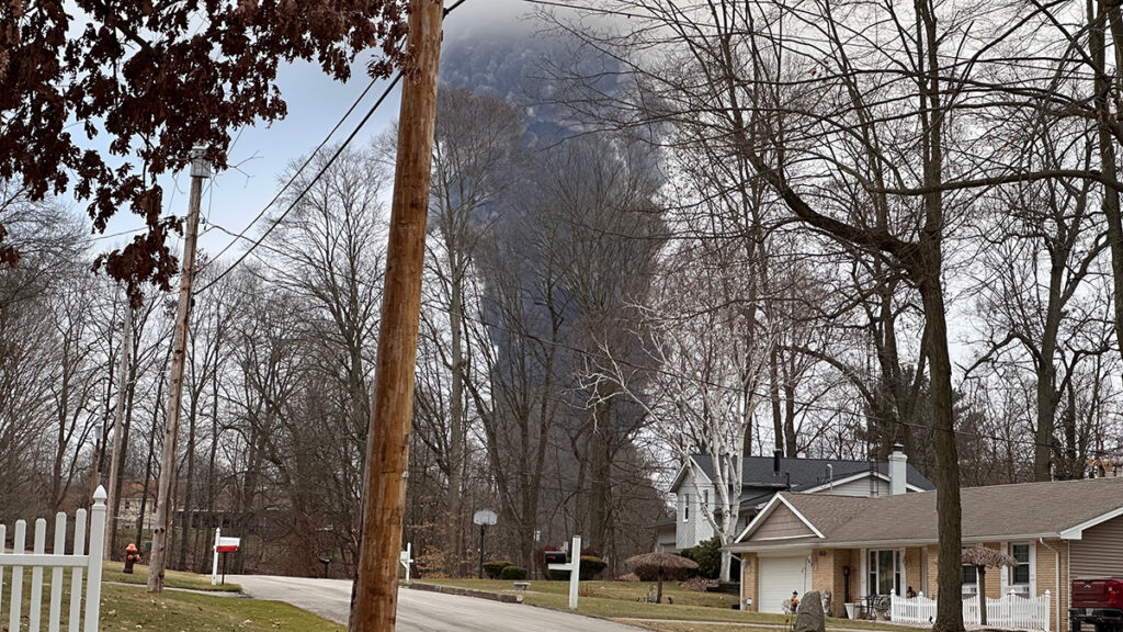 A black plume of smoke behind two single-family homes