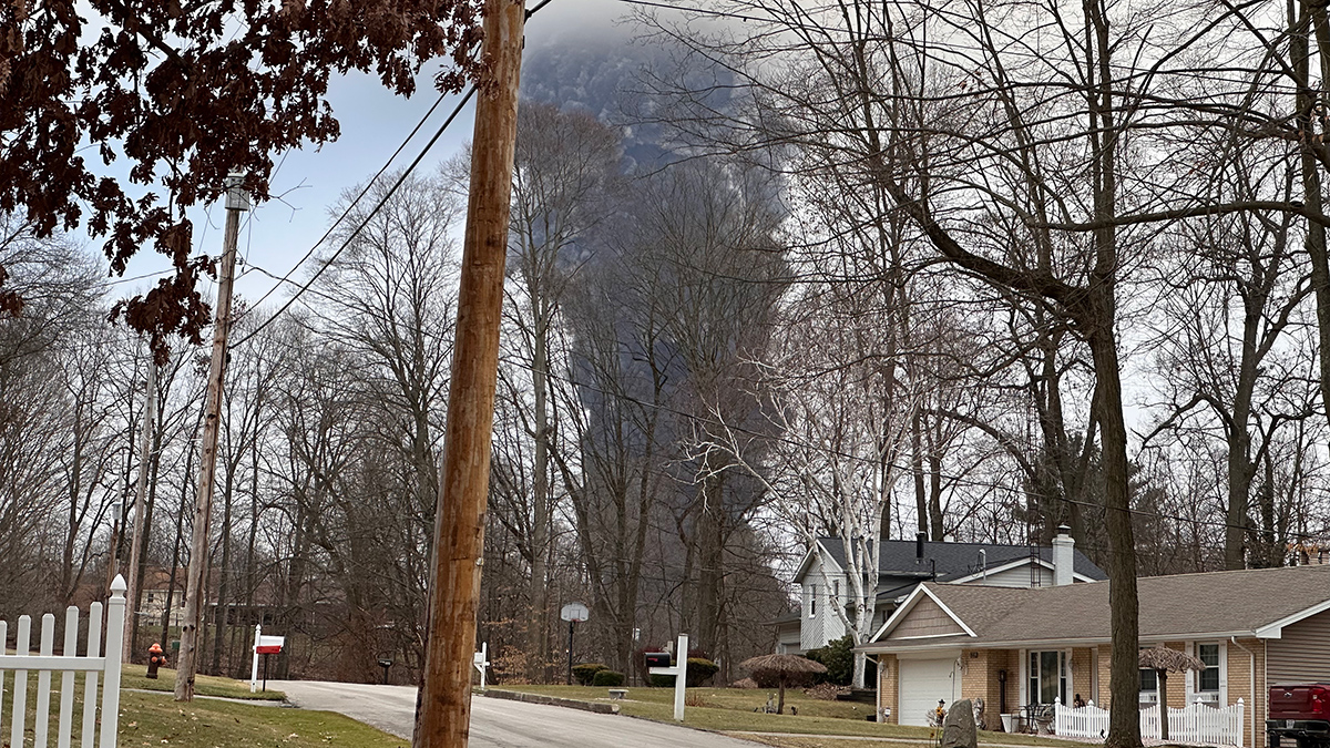 A black plume of smoke behind two single-family homes