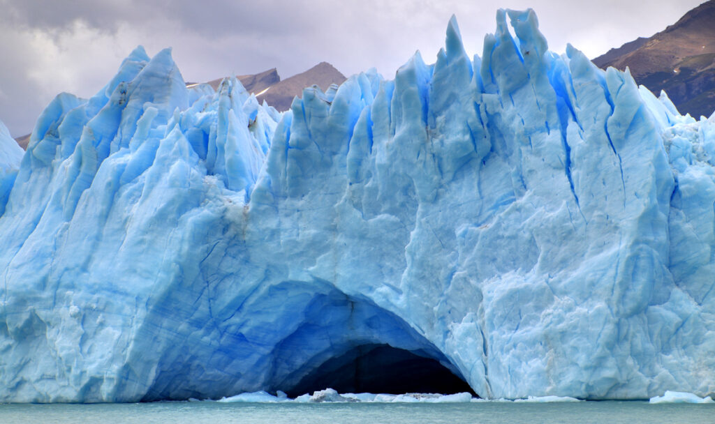 A blue and white glacier over water