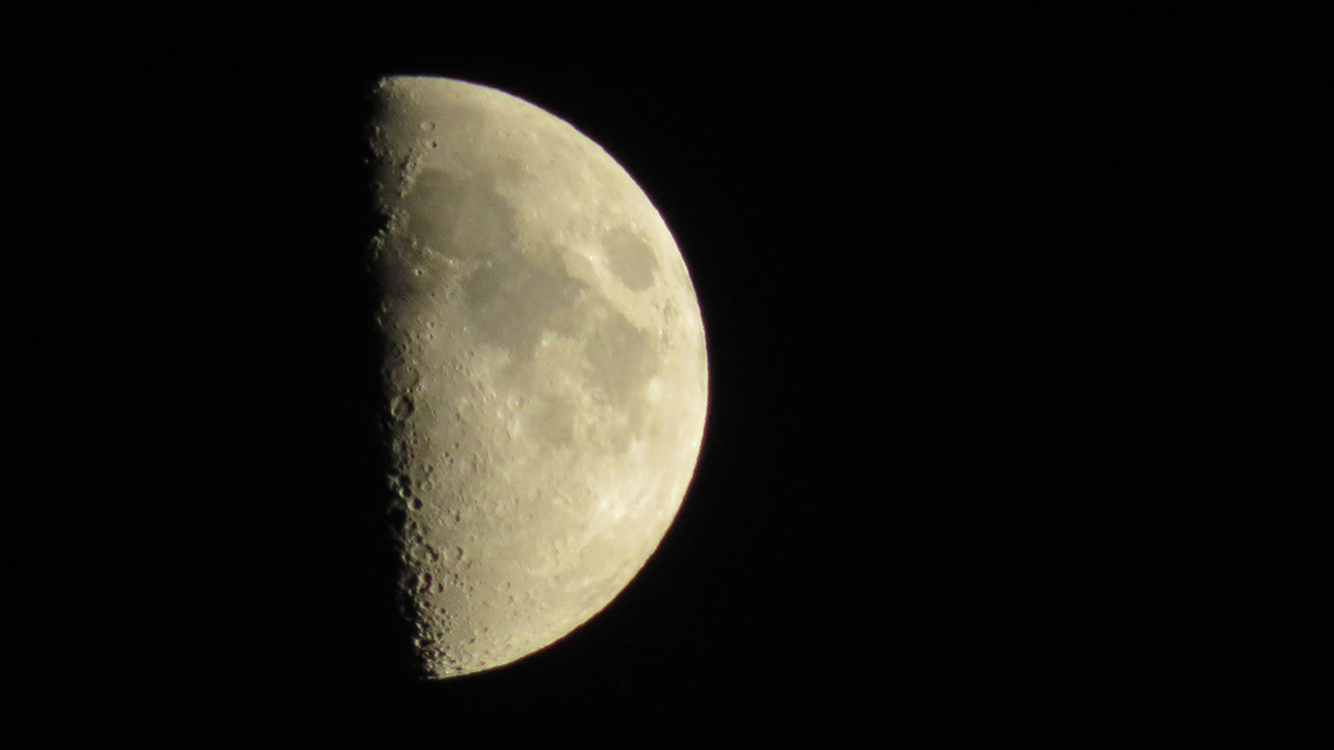 View of the half-illuminated Moon surrounded by black space