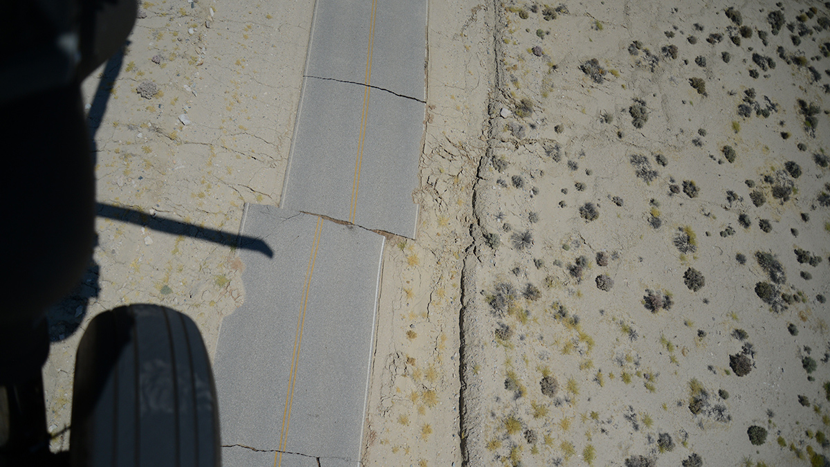 Photo taken from a helicopter of a broken road in a desert landscape
