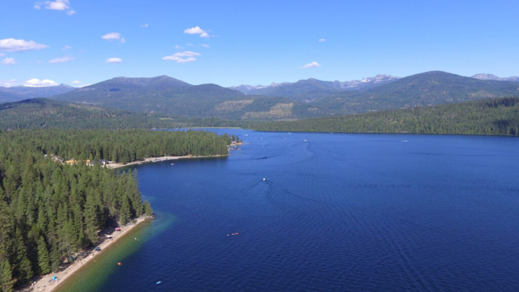 View from above of part of a lake and lakeshore with mountains in the background